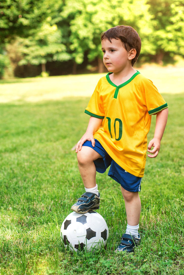 Young child in Brazil soccer T-shirt standing with soccer ball